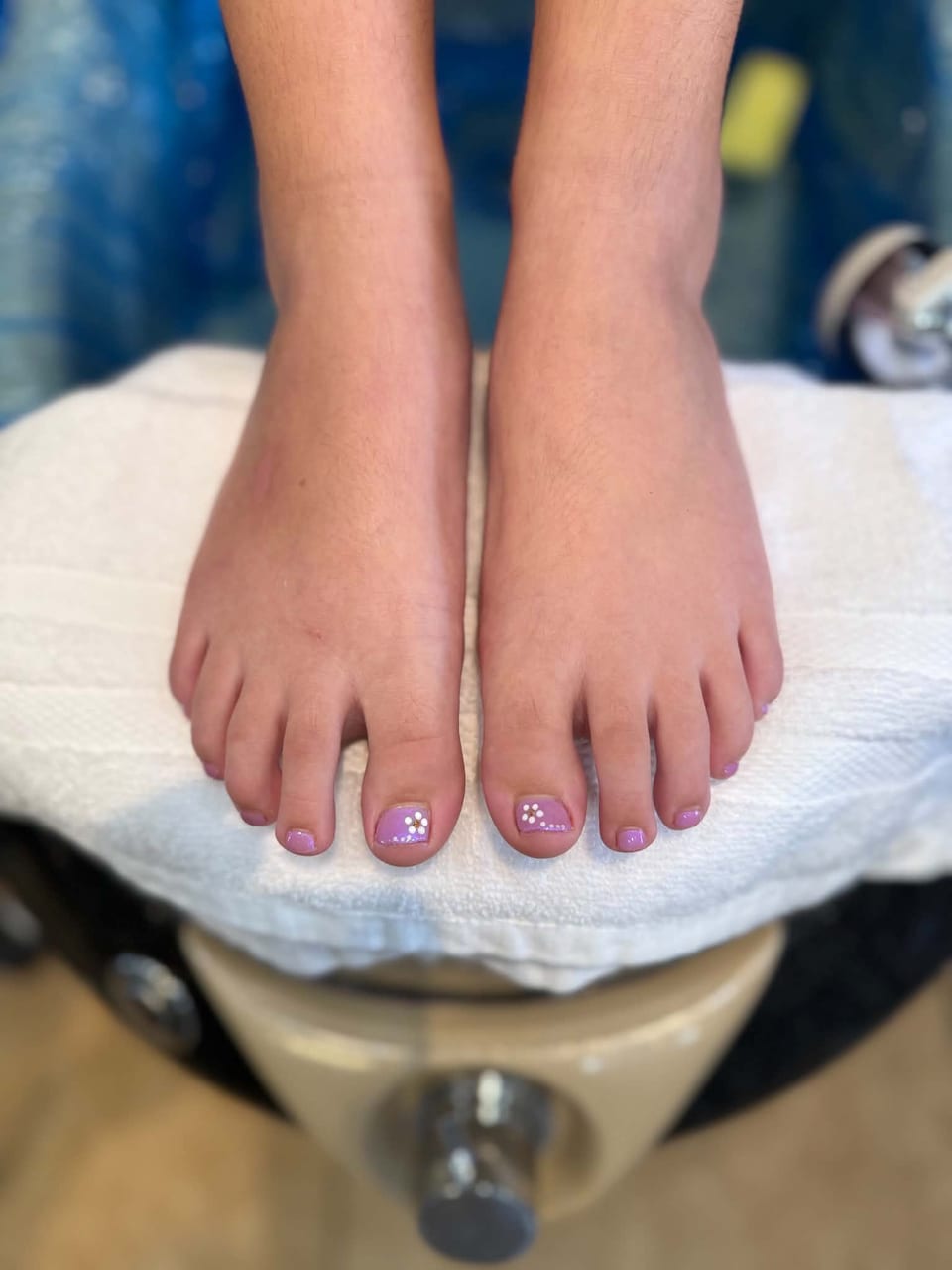 A child’s pedicure in soft lilac with small white flowers